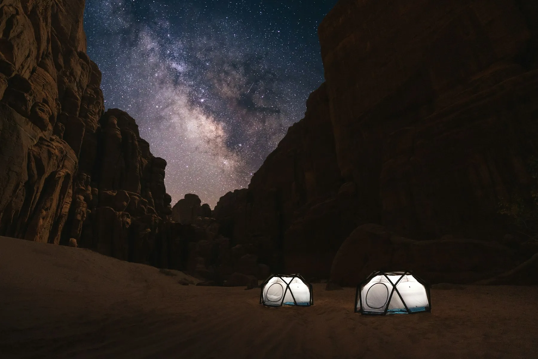 Domos geodésicos iluminados de noche en un cañón del desierto